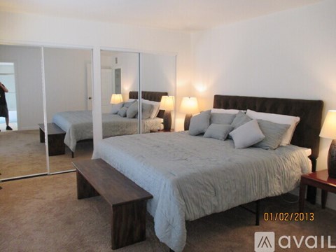 A bedroom with a large bed and a mirror.