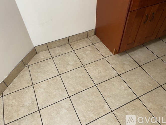 A kitchen with a tile floor and a wooden cabinet.
