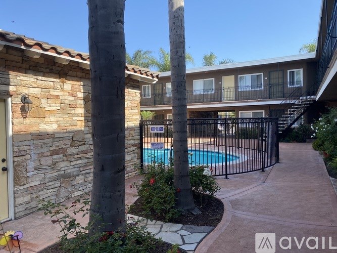 A pool surrounded by a black fence and a stone building.
