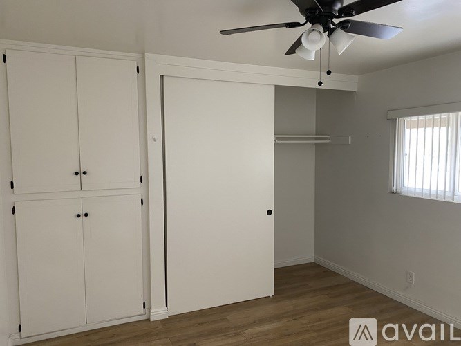 A room with a ceiling fan and two white cabinets.