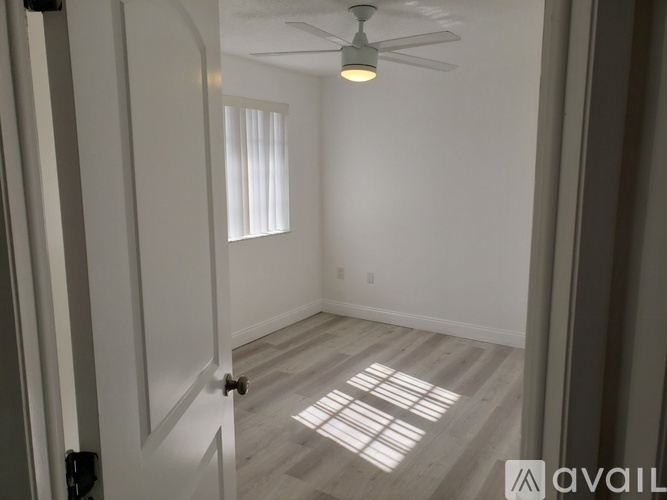 A room with a ceiling fan and a door.