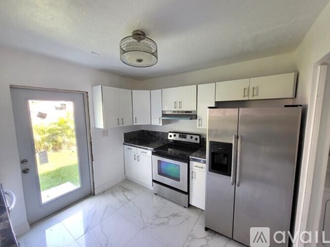 A kitchen with white cabinets and a refrigerator.