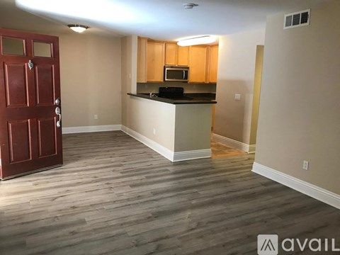 A kitchen area with a red door and wooden cabinets.
