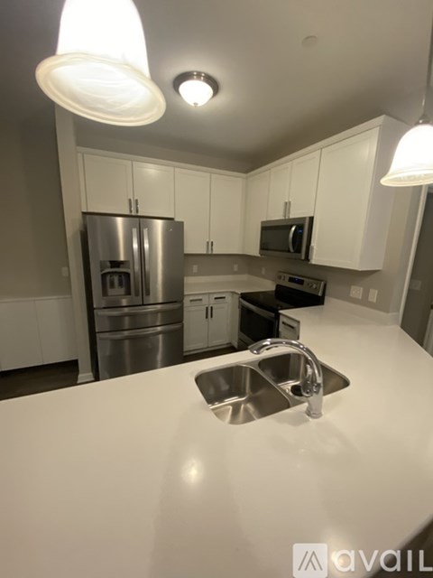 A kitchen with a stainless steel refrigerator and white cabinets.