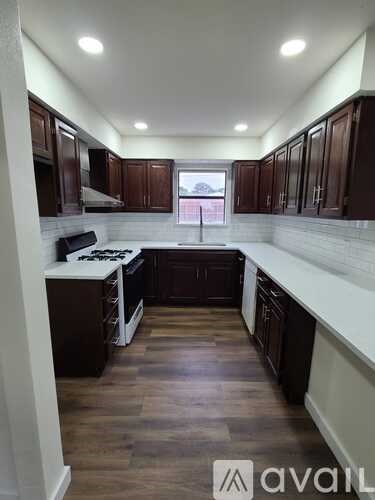 A kitchen with dark wood cabinets and white countertops.