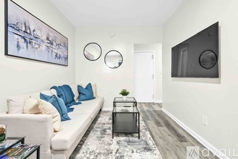 A living room with a white couch and a painting on the wall.
