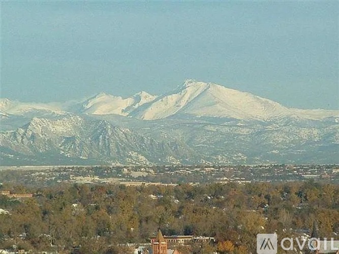 A mountain range with snow-capped peaks in the distance and a town in the foreground.