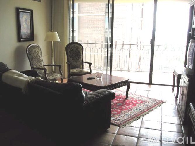 A living room with a couch, two chairs, a table, and a lamp.
