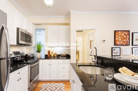 A kitchen with white cabinets and black countertops.