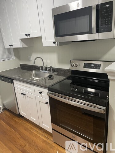A kitchen with white cabinets and a black countertop.