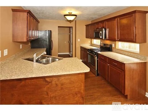 A kitchen with brown cabinets and a black refrigerator.