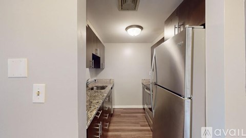 A kitchen with a stainless steel refrigerator and a marble countertop.
