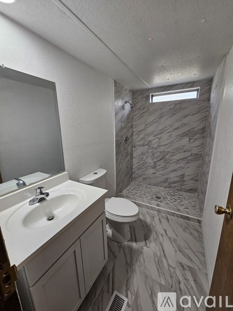 A bathroom with a marble tile shower and a white sink.