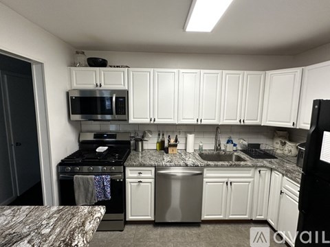 A kitchen with white cabinets and a black refrigerator.