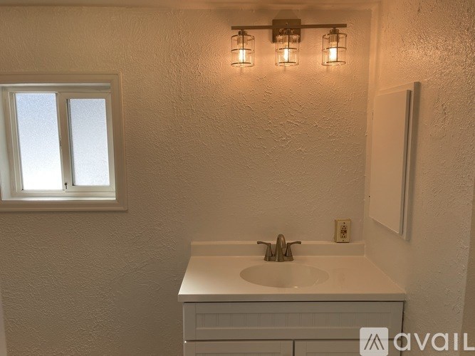 A bathroom with a white sink and a window.