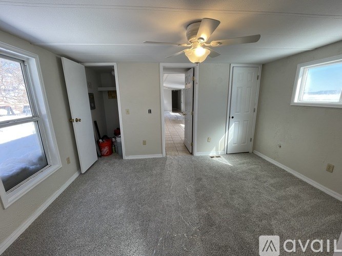 A room with a ceiling fan and carpeted floor.