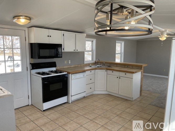 A kitchen with white cabinets and black appliances.