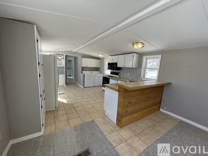 A kitchen with a refrigerator, sink, and cabinets.