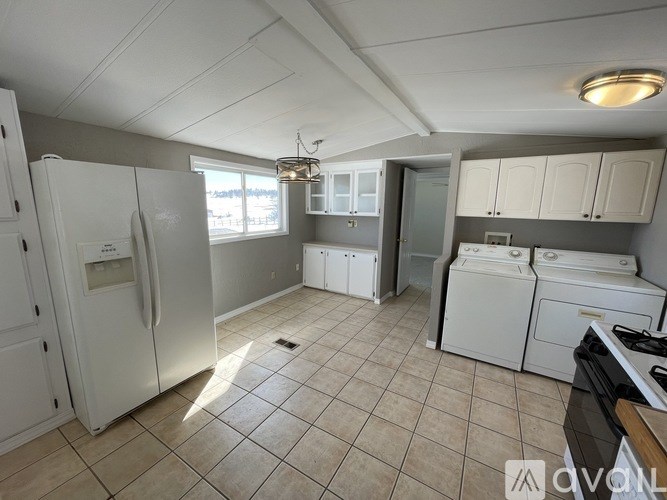 A kitchen with white appliances and a tiled floor.