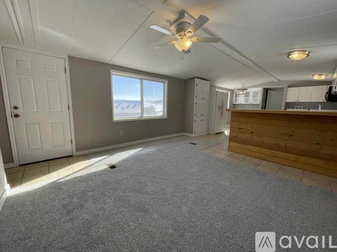 A room with a ceiling fan and a large window.