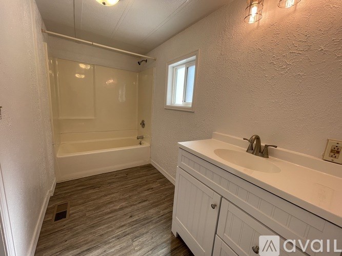 A bathroom with a white sink, a bathtub, and a window.