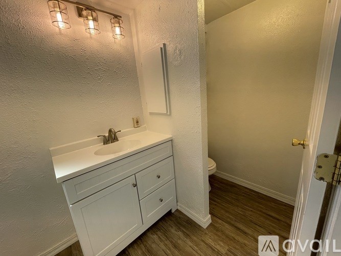 A white bathroom with a sink, toilet, and a mirror.