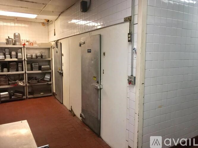 A kitchen with a white tiled wall and a metal fridge.