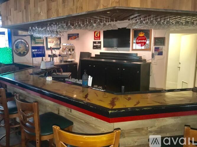 A bar with a black counter and wooden chairs.