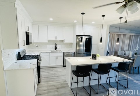 A modern kitchen with white cabinets and black chairs.