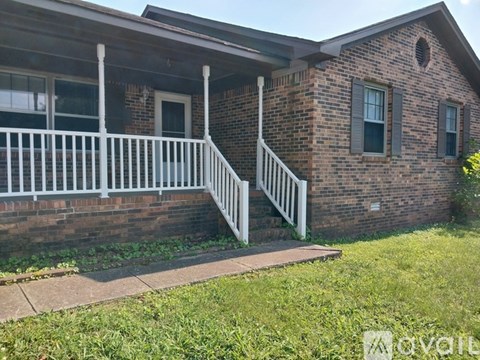 A brick house with a white porch and a small front yard.