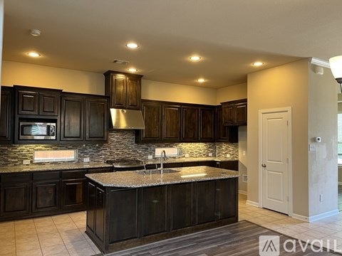 A kitchen with dark wood cabinets and a granite countertop.