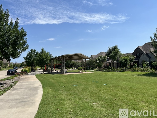 A sunny day at a park with a walking path and a gazebo.