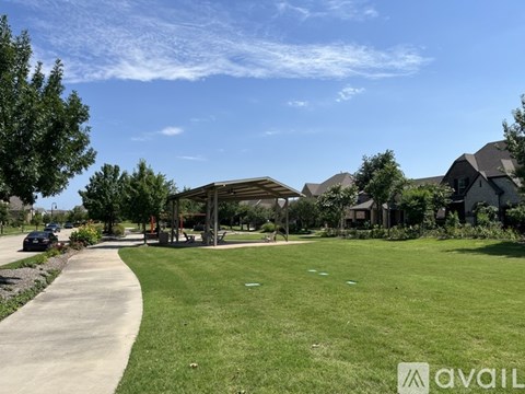 A sunny day at a park with a walking path and a gazebo.