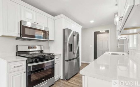 A modern kitchen with white cabinets and stainless steel appliances.