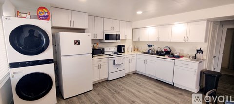A kitchen with white cabinets and appliances, including a washing machine and a refrigerator.