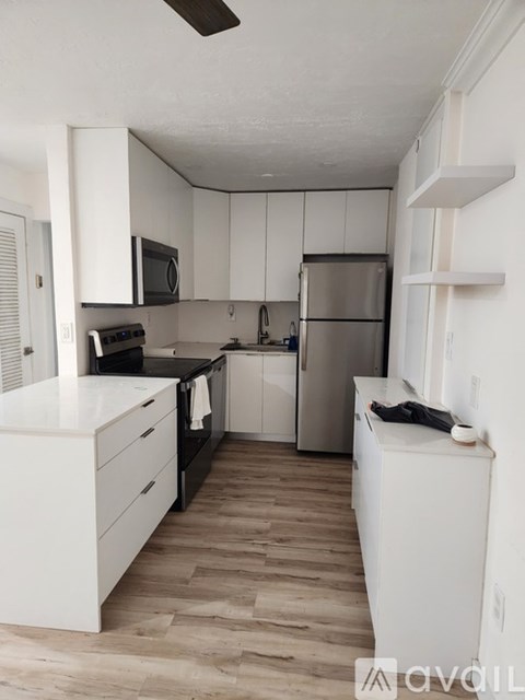 A kitchen with white cabinets and a wooden floor.