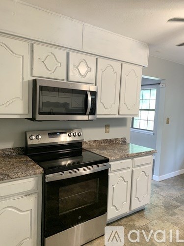 A kitchen with a black stove top oven and microwave above it.