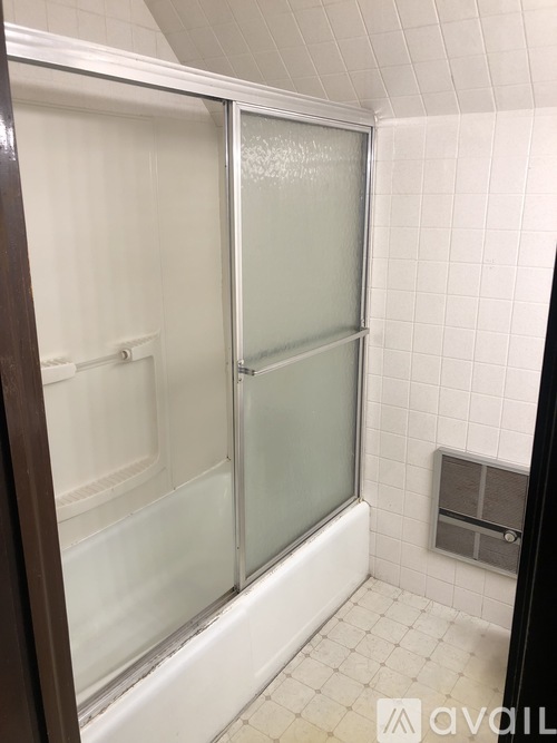 A bathroom with a walk-in shower and a white tiled floor.