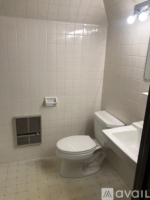 A white toilet in a small bathroom with a white sink.