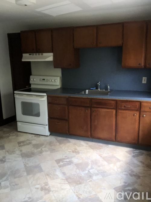 A kitchen with a white stove and brown cabinets.