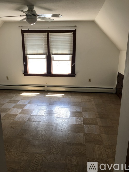 A room with a ceiling fan and a window with blinds.