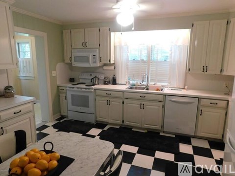 A kitchen with white cabinets and a black and white checkered floor.