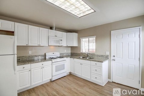 A kitchen with white cabinets and a granite countertop.
