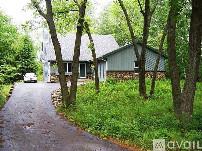 A house with a driveway and trees in front of it.