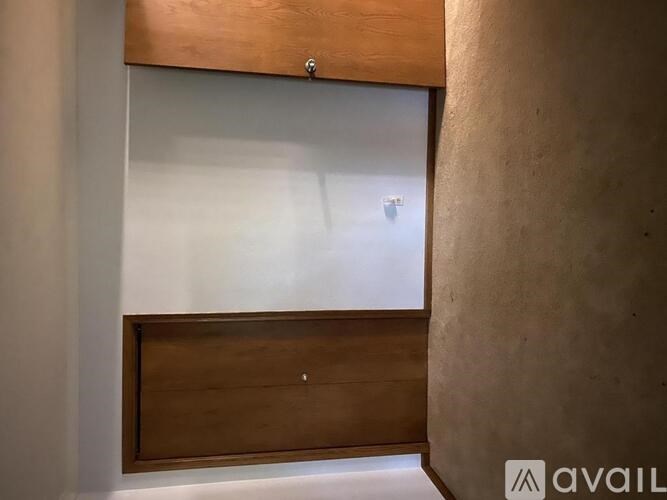 A wooden cabinet with a glass door is mounted on a wall.