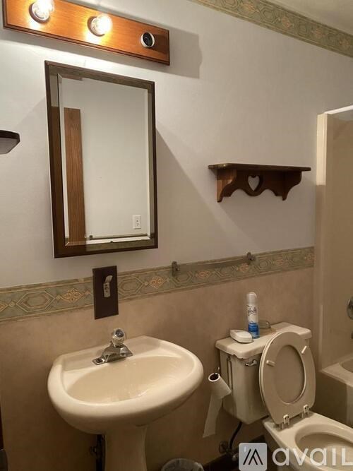 A bathroom with a sink, mirror, and toilet.