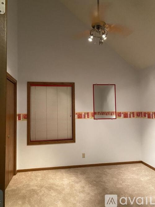 A room with a ceiling fan and a window with blinds.