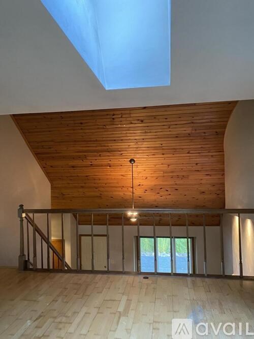 A wooden ceiling with a skylight and a staircase with a metal railing.