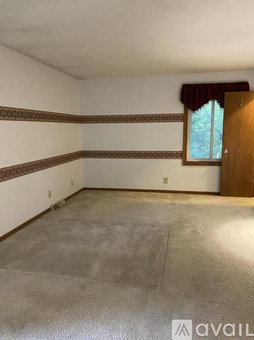 A room with a window and a door is available for rent.