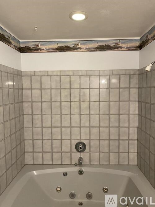 A bathroom with a white tub and grey tiles.